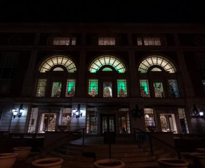 Exterior of History Center at night. Christmas trees can be seen in the windows on the first and second levels.