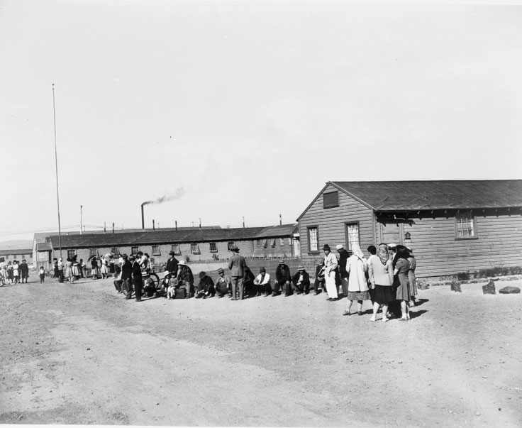 Barracks with people milling outside -- Japanese internment camp