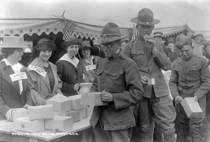 Women serve boxed lunches to soldiers.