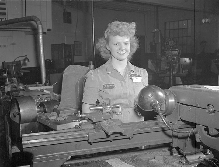 Woman in factory uniform with machinery in front of her