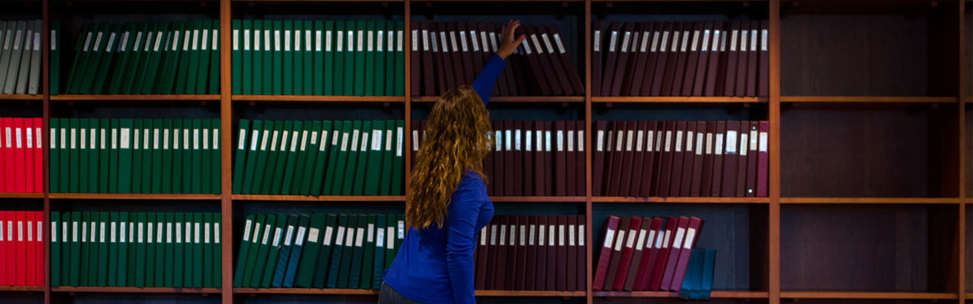 Woman reaching for books in library